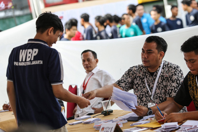 Petugas memberikan surat suara kepada warga binaan untuk mencoblos di TPS Khusus 905, Lapas Narkotika Kelas IIA Jakarta, Cipinang, Jakarta, Rabu (27/11/2024). Foto: ANTARA FOTO/Asprilla Dwi Adha