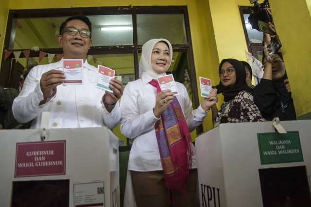 Calon gubernur DKI Jakarta nomor urut 1 Ridwan Kamil bersama istri sekaligus Anggota Komisi VIII DPR RI Atalia Praratya menunjukkan surat suara sebelum menggunakan hak pilihnya pada pilkada 2024 di TPS 23, Bandung, Rabu (27/11/2024). Foto: Novrian Arbi/ANTARA FOTO