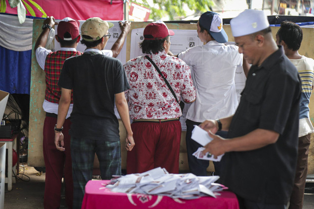 Anggota Kelompok Penyelenggara Pemungutan Suara (KPPS) berbusana seragam sekolah mempersiapkan TPS 005, Petamburan, Tanah Abang, Jakarta, Rabu (27/11/2024). Foto: Iqbal Firdaus/kumparan