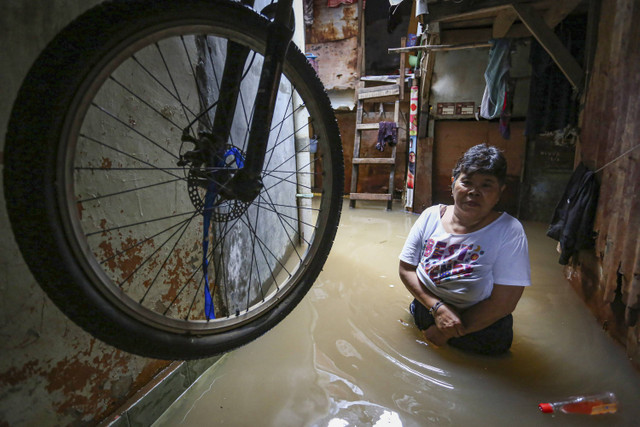 Warga melintasi area rumahnya yang terendam banjir luapan Sungai Ciliwung di Kebon Pala, Kampung Melayu, Jatinegara, Jakarta, Kamis (28/11/2024). Foto: Idlan Dziqri Mahmudi/ANTARA FOTO