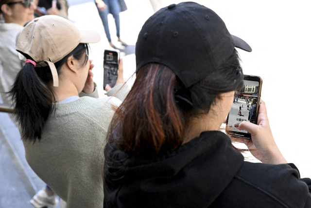 Kaum muda melihat ponsel mereka di Melbourne pada 28 November 2024 ketika Australia berupaya melarang anak-anak di bawah 16 tahun dari media sosial dengan klaim bahwa platform media sosial telah dinodai oleh perundungan dunia maya. Foto: William West/AFP