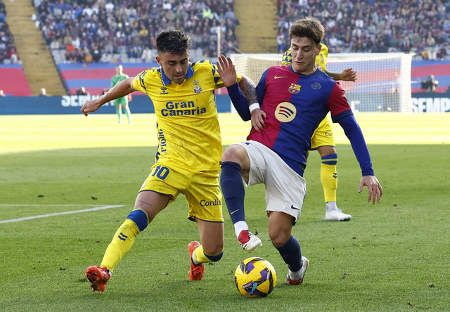 Alberto Moleiro dari Las Palmas berebut bola dengan Pablo Torre dari FC Barcelona pada pertandingan La Liga, 30 November 2024. Foto: REUTERS/Albert Gea