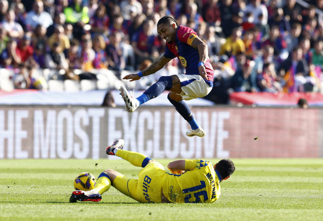 Pemain Barcelona Raphinha berebut bola dengan Scott McKenna dari Las Palmas. Foto: REUTERS/Albert Gea