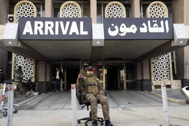 Seorang pejuang oposisi Suriah duduk di kursi kantor sambil berpose untuk berfoto di gerbang kedatangan bandara internasional Aleppo di Aleppo, Suriah, Senin, 2 Desember 2024. Foto: Omar Albam/AP Photo