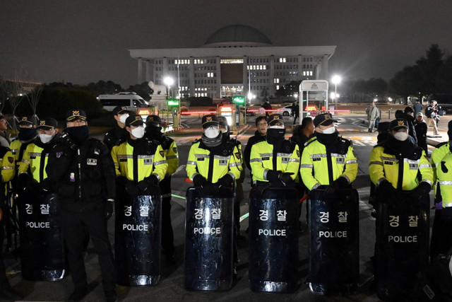 Polisi berjaga setelah Presiden Korea Selatan Yoon Suk Yeol mengumumkan darurat militer di depan gerbang utama Majelis Nasional di Seoul, Korea Selatan, Selasa (3/12/2024). Foto: JUNG YEON-JE / AFP