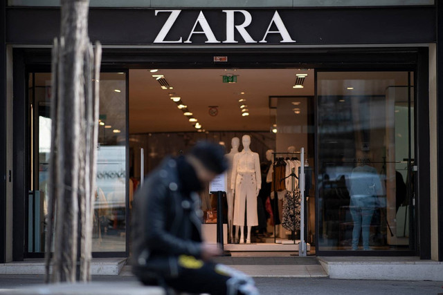 Seorang pria duduk di depan toko busana siap pakai Zara di pusat kota Nantes, Prancis barat, pada 25 Maret 2021. Foto: LOIC VENANCE/AFP