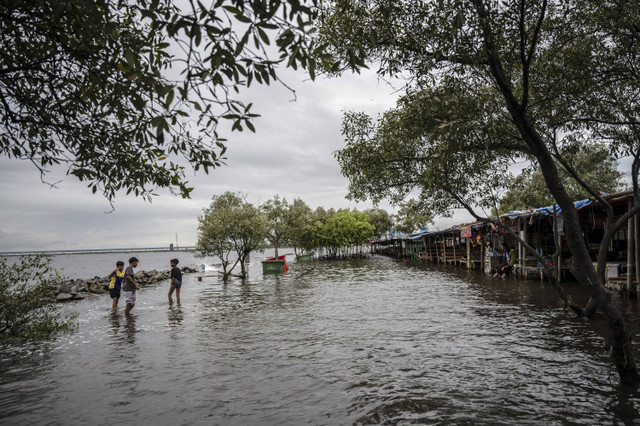 Sejumlah anak berjalan melintasi banjir rob di kawasan Pantai Marunda, Jakarta, Rabu (4/12/2024). Foto: Aprillio Akbar/ANTARA FOTO