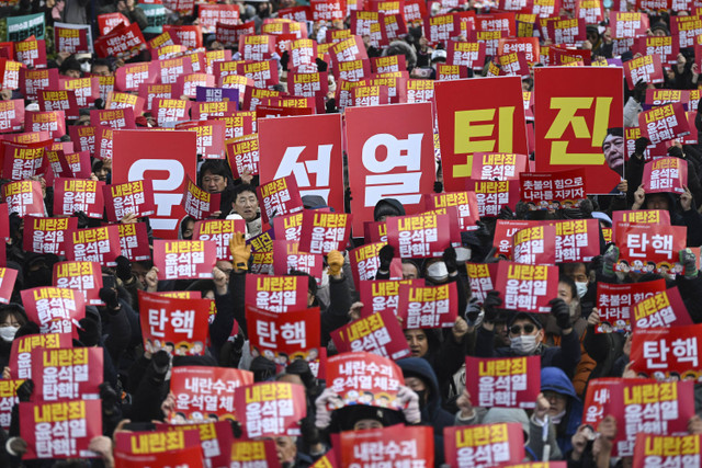 Sejumlah pengunjuk rasa membentangkan poster saat mengikuti aksi penggulingan Yoon di luar Majelis Nasional, Seoul, Korea Selatan, Sabtu (7/12/2024). Foto: Jung Yeon-je/AFP