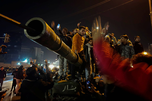 Warga Suriah merayakan kedatangan pejuang oposisi di Damaskus, Suriah, Minggu (8/12/2024). Foto: Omar Sanadiki/AP PHOTO