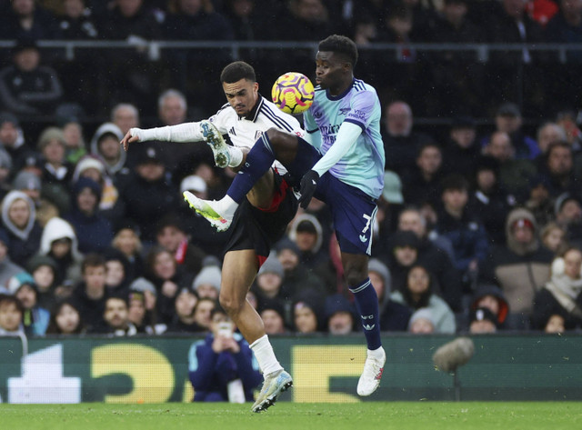 Pemain Fulham Antonee Robinson beraksi dengan pemain Arsenal Bukayo Saka pada pertandingan Liga Inggris antara Fulham melawan Arsenal di Craven Cottage, London, Inggris, Minggu (8/12/2024). Foto: Isabel Infantes/REUTERS