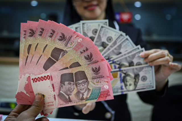 Seorang petugas menunjukan pecahan Dolar AS dan Rupiah di salah satu tempat penukaran mata uang asing di Kwitang, Jakarta, Senin (9/12/2024). Foto: Iqbal Firdaus/kumparan