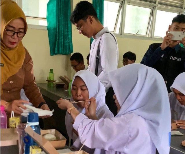 Seorang siswi SMAN 1 Pontianak membantu teman sebangkunya makan. Foto: Yulia Ramadhiyanti/Hi!Pontianak