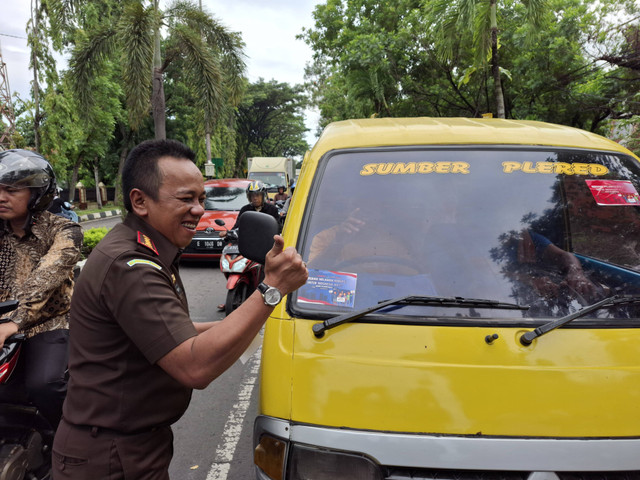 Kepala Kejaksaan Negeri (Kajari) Kabupaten Cirebon, Yudhi Kurniawan, saat menempelkan stiker antikorupsi di kendaraan angkutan umum. Foto: Tarjoni/Ciremaitoday