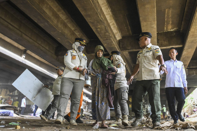 Sejumlah petugas mengevakuasi seorang warga saat membersihkan bekas hunian semi permanen di kolong Tol Angke, Jalembar Baru, Jakarta, Rabu (11/12/2024).  Foto: Sulthony Hasanuddin/ANTARA FOTO 