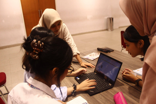 Mahasiswa berdiskusi di depan laptop, mencerminkan tekanan akademik yang kerap memicu praktik penyimpangan seperti penggunaan jasa joki.