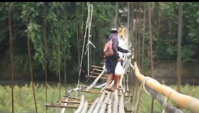 Potret warga yang sedang melintasi jembatan miring dan rusak di wilayah Garut Selatan. (Foto: Istimewa)