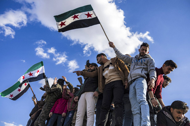 Orang-orang merayakan penggulingan presiden Suriah Bashar al-Assad di dekat patung Pedang Damaskus yang terkenal di Umayyad Square di pusat kota Damaskus pada tanggal 13 Desember 2024. Foto: Sameer Al-Doumy/AFP