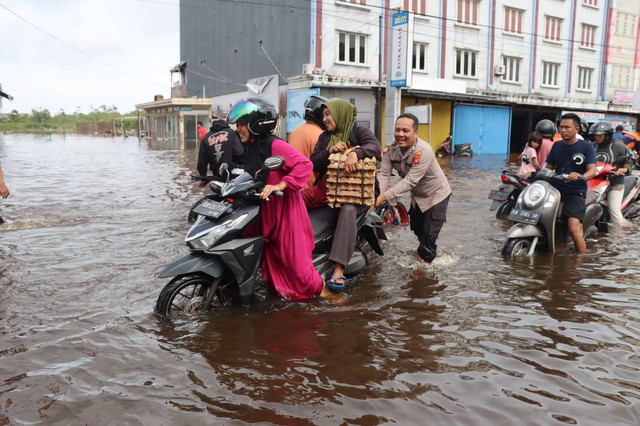 Personel Polres Ketapang bantu mendorong motor warga yang mogok saat melewati banjir di ruas jalan Kota Ketapang. Foto: Dok. Polres Ketapang