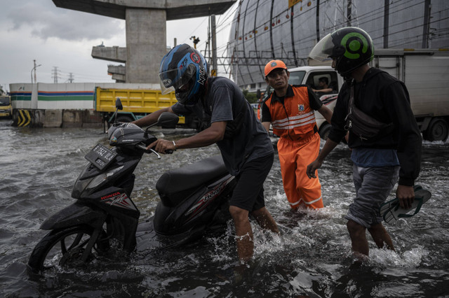 Pengendara sepeda motor mendorong motornya saat banjir rob di Jalan R.E. Martadinata, Tanjung Priok, Jakarta, Selasa (17/12/2024). Foto: Aprillio Akbar/ANTARA FOTO