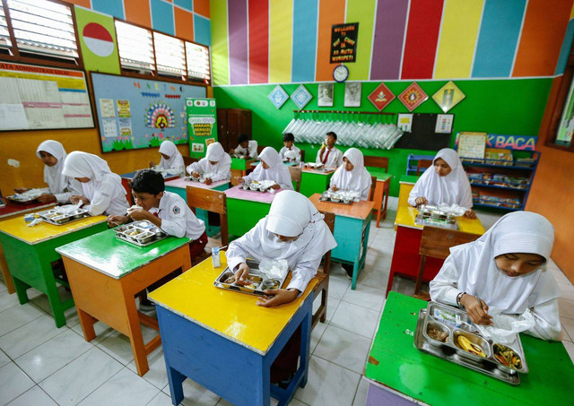 Murid-murid sekolah SD Muhammadiyah 1 Wonopeti sedang menikmati paket makanan bergizi gratis yang disediakan oleh Mitra UMKM yang berpartisipasi dalam proses penyediaan menu makanan sehat dan bergizi melalui uji coba program Makan Bergizi Gratis di Kulon Progo. (Foto : Istimewa)