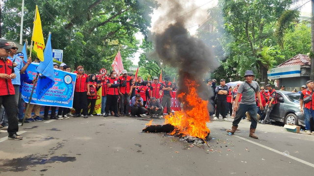 Buruh Sumsel saat membakar ban di depan Kantor Gubernur Sumsel. Foto : Abdullah Toriq/Urban Id