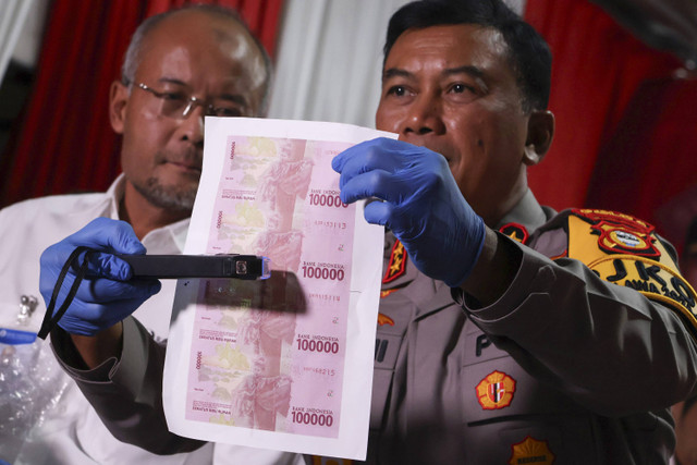 Kapolda Sulawesi Selatan Irjen Pol Yudhiawan (kanan) mengecek barang bukti uang palsu menggunakan detektor mata uang (money detector) saat konferensi pers di Mapolres Kabupaten Gowa, Sulawesi Selatan, Kamis (19/12/2024). Foto: Arnas Padda/ANTARA FOTO