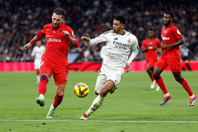 Pemain Real Madrid Jude Bellingham berebut bola dengan pemain Sevilla Nemanja Gudelj pada pertandingan Liga Spanyol di Santiago Bernabeu, Madrid, Spanyol, Minggu (22/12/2024). Foto: Juan Medina/REUTERS