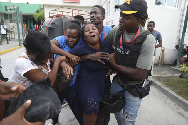 Istri seorang jurnalis, yang ditembak dalam serangan gerombolan bersenjata di Rumah Sakit Umum, menangis ketika ambulans tiba dengan membawa jenazahnya, di rumah sakit yang berbeda di Port-au-Prince, Haiti, Selasa, 24 Desember 2024.  Foto: Jean Feguens Regala/AP Photo