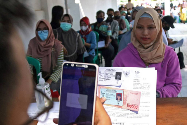 Petugas Kantor Pos memotret warga penerima bantuan sosial atau Bansos di kantor Pos Bandar Lampung, Lampung, Kamis (14/4/2022).  Foto: Ardiansyah/ANTARA FOTO