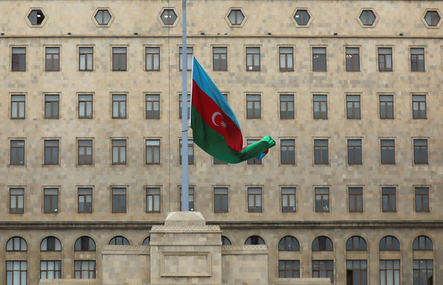 Bendera negara Azeri berkibar setengah tiang saat negara itu memperingati hari berkabung nasional bagi para korban kecelakaan pesawat penumpang Embraer Azerbaijan Airlines di dekat kota Aktau, Kazakh, di luar Gedung Pemerintah di Baku, Azerbaijan. Foto: REUTERS/Aziz Karimov