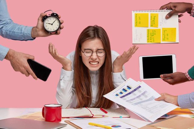 Ilustrasi seorang wanita yang tampak stres dan kelelahan akibat toxic productivity. Photo by https://www.freepik.com/free-photo/brunette-woman-sitting-desk-surrounded-with-gadgets-papers_13556711.htm#fromView=search&page=1&position=33&uuid=ec6b698d-cc49-4425-bdde-0cddc3821baf&new_detail=true