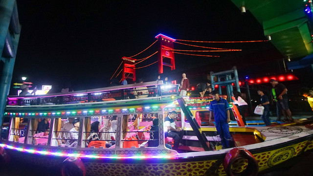 Warna-waeni lampu menghias kapal tradisional di bawah Jembatan Ampera yang dipersiapkan membawa pengunjung menyusur sungai jelang tahun baru di Kota Musi, Sabti (28/12) Foto: ary/urban id