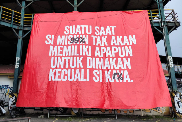 Spanduk bertuliskan 'Suatu Saat Si Miskin -99%- Tak Akan Memiliki Apapun Untuk Dimakan Kecuali Si Kaya -1%-' muncul di Tempat Khusus Parkir (TKP) Abu Bakar Ali, Kota Yogyakarta, Senin (30/12/2024).
 Foto: Arfiansyah Panji Purnandaru/kumparan