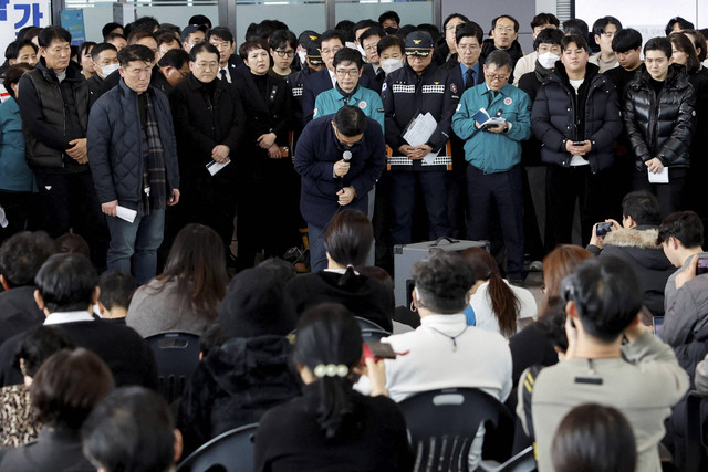 Seorang pejabat dari Jeju Air membungkuk untuk meminta maaf kepada anggota keluarga korban kecelakaan pesawat Jeju Air saat konferensi pers di Bandara Internasional Muan, di Muan, Korea Selatan, Senin (30/12/2024). Foto: Kim Soo-Hyeon/REUTERS