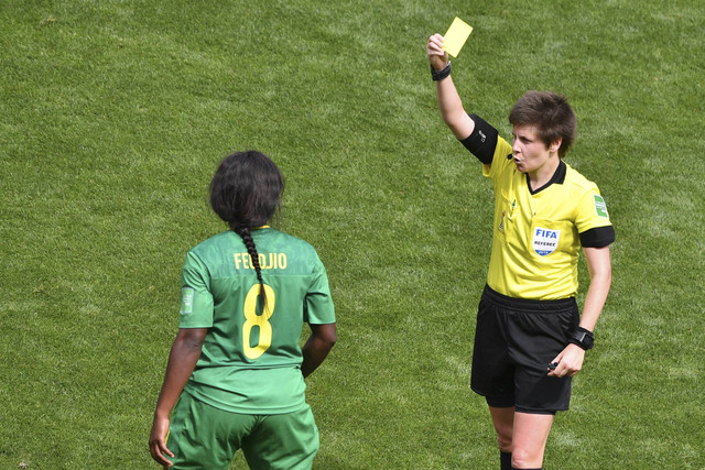 Wasit asal Australia, Casey Reibelt (kanan) menunjukkan kartu kuning kepada gelandang Kamerun, Raissa Feudjio dalam pertandingan sepak bola Grup E Piala Dunia Wanita 2019 antara Belanda dan Kamerun di Stadion Hainaut, Valencienne, Prancis. Foto: Philippe Huguen/AFP