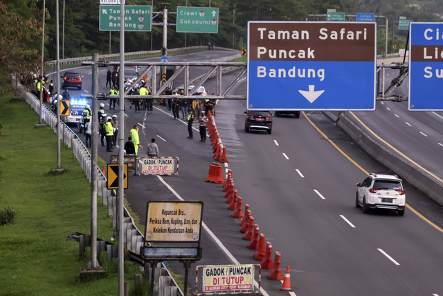 Petugas kepolisian melakukan penutupan jalur di pintu keluar tol Gadog, Ciawi, Kabupaten Bogor, Jawa Barat, Selasa (31/12/2024).  Foto: Yulius Satria Wijaya/ANTARA FOTO