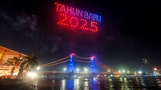 Aksi ratusan drone membentuk ucapan selamat tahun baru 2025 di langit dengan latar Jembatan Ampera saat momen pergantian tahun baru di Palembang, Rabu (1/1) Foto: ary priyanto/urban id