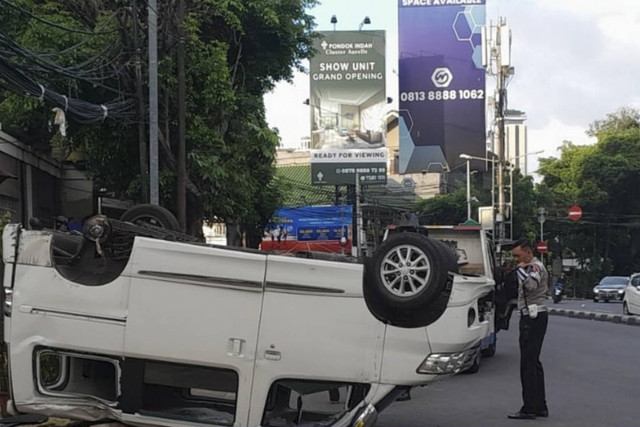 Petugas kepolisian meninjau sebuah mobil yang terguling di Jl. Sisingamangaraja, Jakarta Selatan, Rabu (1/1/2025). Foto: X/ @TMCPoldaMetro