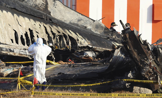 Anggota tim investigasi ilmiah polisi melakukan operasi pencarian di dekat lokasi pesawat Boeing 737-800 milik Jeju Air jatuh dan terbakar di Bandara Internasional Muan, Korea Selatan, Rabu (1/1/2025). Foto: STR/AFP