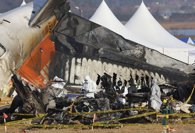 Anggota tim investigasi ilmiah polisi melakukan operasi pencarian di dekat lokasi pesawat Boeing 737-800 milik Jeju Air jatuh dan terbakar di Bandara Internasional Muan, Korea Selatan, Rabu (1/1/2025). Foto: STR/AFP