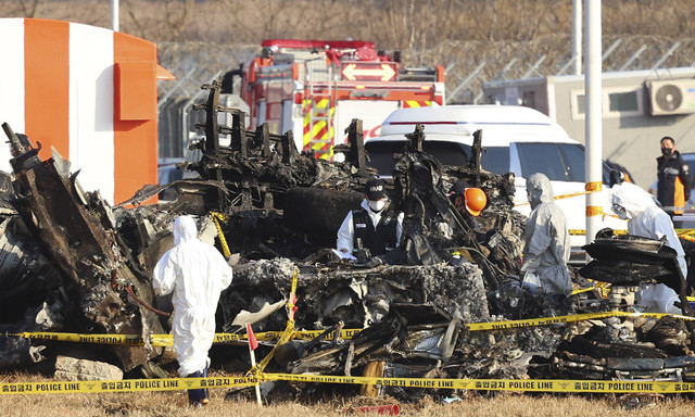 Anggota tim investigasi ilmiah polisi melakukan operasi pencarian di dekat lokasi pesawat Boeing 737-800 milik Jeju Air jatuh dan terbakar di Bandara Internasional Muan, Korea Selatan, Rabu (1/1/2025). Foto: STR/AFP