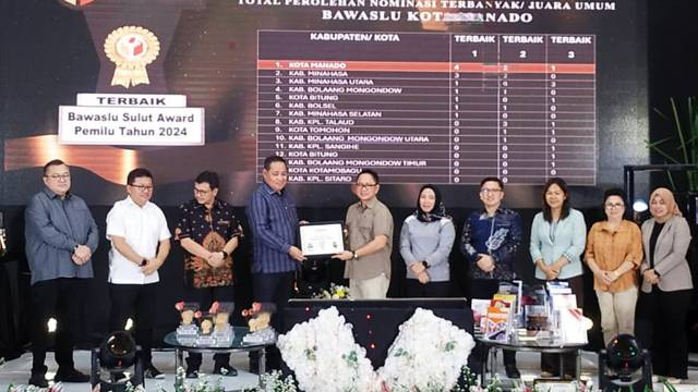 Anggota Bawaslu RI, Herwyn Malonda, saat menyerahkan piagam penghargaan kepada anggota Bawaslu Kota Manado, Heard Runtuwene, pada penyelenggaraan Bawaslu Sulut Award 2024.