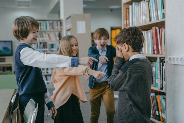 Bullying di sekolah (sumber: https://www.pexels.com/photo/a-group-of-children-laughing-at-a-boy-in-a-library-7929423/)