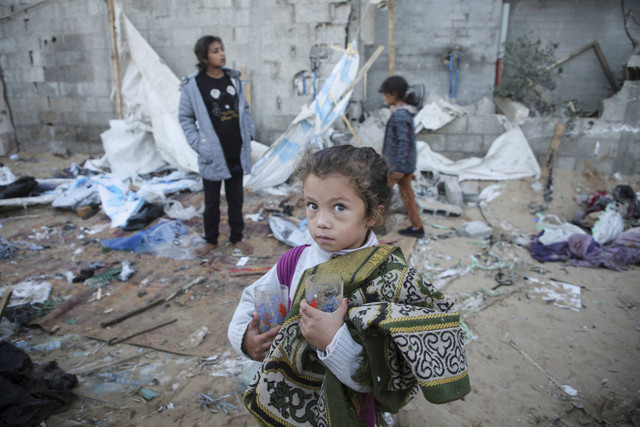 Seorang gadis Palestina memegang kacamata di tangannya saat dia berdiri di tengah-tengah kerusakan tenda usai serangan Israel terhadap kamp pengungsian sementara di Mawasi Khan Yunis di Jalur Gaza selatan, Kamis (2/1/2025). Foto: Hatem Khaled/REUTERS