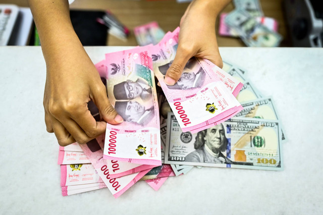 Petugas menghitung uang pecahan dolar AS dan rupiah di gerai penukaran mata uang asing di Jakarta, Jumat (2/1/2025). Foto: ANTARA FOTO/Rivan Awal Lingga