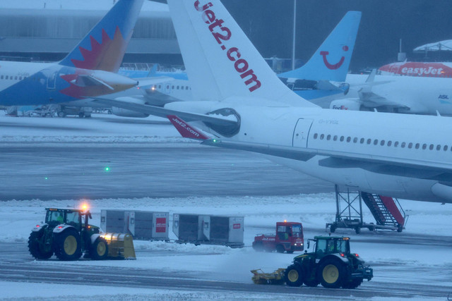 Petugas membersihkan salju dari sekitar pesawat setelah hujan salju yang menyebabkan penutupan sementara Bandara Manchester di Manchester, Inggris, Minggu (5/1/2025). Foto: Phil Noble/REUTERS