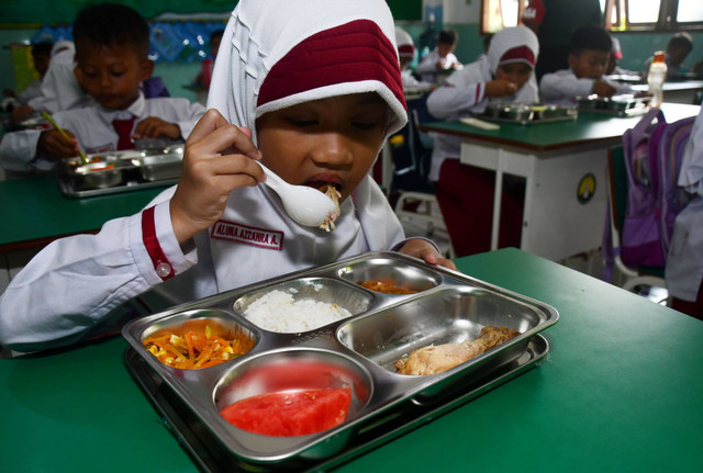 Sejumlah murid menikmati paket makan program Makan Bergizi Gratis (MBG) untuk dibagikan di kelasnya pada hari pertama di MI Islamiyah, Kota Madiun, Jawa Timur, Senin (6/1/2025).  Foto: Siswowidodo/ANTARA FOTO