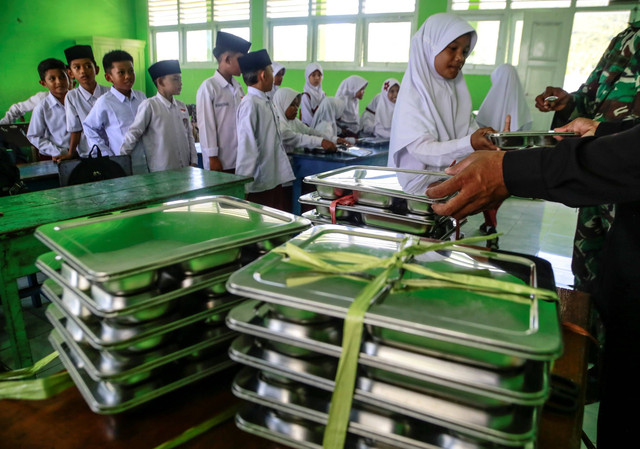 Personel TNI AD bersama guru membagikan makanan bergizi gratis kepada siswa di Madrasah Ibtidaiyah Negeri 2 Kota Ternate, Maluku Utara, Senin (6/1/2025). Foto: Andri Saputra/ANTARA FOTO