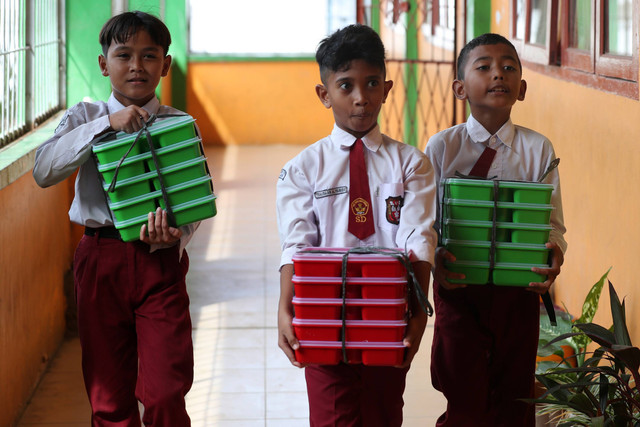 Pelajar membawa paket makanan pada pelaksanaan program Makan Bergizi Gratis (MBG) hari pertama di SD Negeri 56 Banda Aceh, Aceh, Senin (6/1/2025). Foto: Irwansyah Putra/ANTARA FOTO