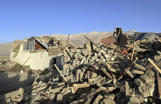 Dalam foto yang dirilis oleh Kantor Berita Xinhua ini, orang-orang berdiri di tengah-tengah rumah yang rusak setelah gempa bumi di Desa Tonglai, Kotapraja Changsuo Dingri di Xigaze, Daerah Otonomi Tibet di barat daya Tiongkok, Selasa (7/1/2025). Foto: Xinhua via AP Photo